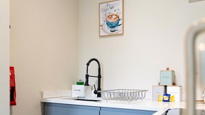 A kitchen with a sink, a coffee machine, and a tea and coffee box. - Stylish 1-bed Stay in the Heart of Barnard Castle (Barnard Castle)