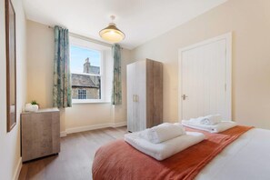 Une chambre d’hôtel avec un lit, une armoire, un bureau et une fenêtre avec des rideaux.