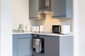 A modern kitchen with grey cabinets, a built-in oven, a microwave, and a toaster. - Stylish 1-bed Stay in the Heart of Barnard Castle (Barnard Castle)