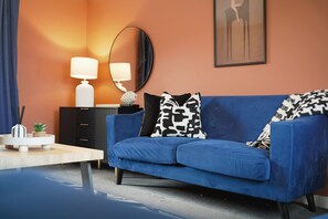 A modern living room with a blue sofa, a side table, a lamp, a mirror, and a framed picture on the wall. - Teesside 3BR Family Retreat Sleeps 5 by Stay With Us (Stockton-on-Tees)