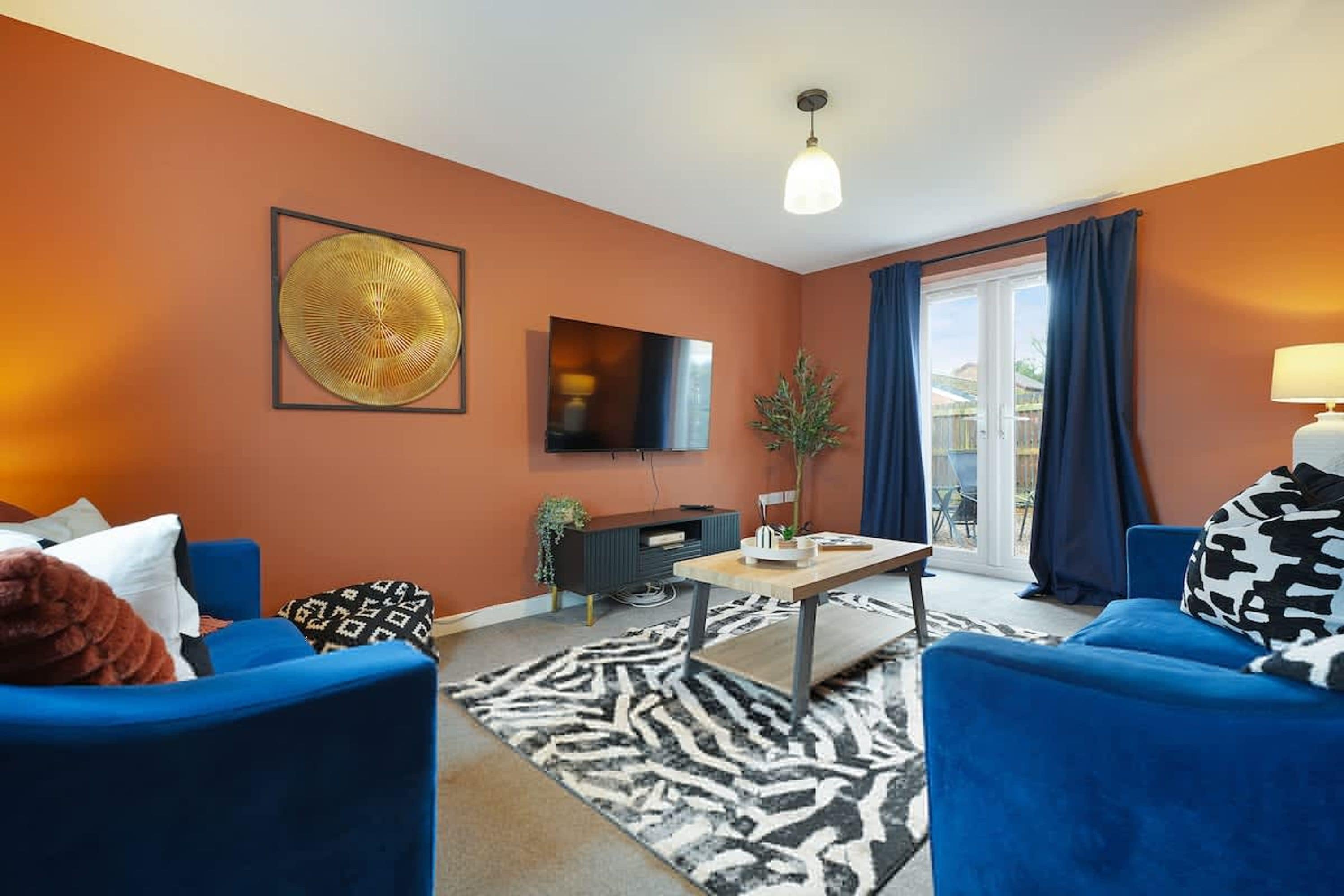 A living room with blue sofas, a flat-screen TV, a zebra-patterned rug, and a large wall art piece.