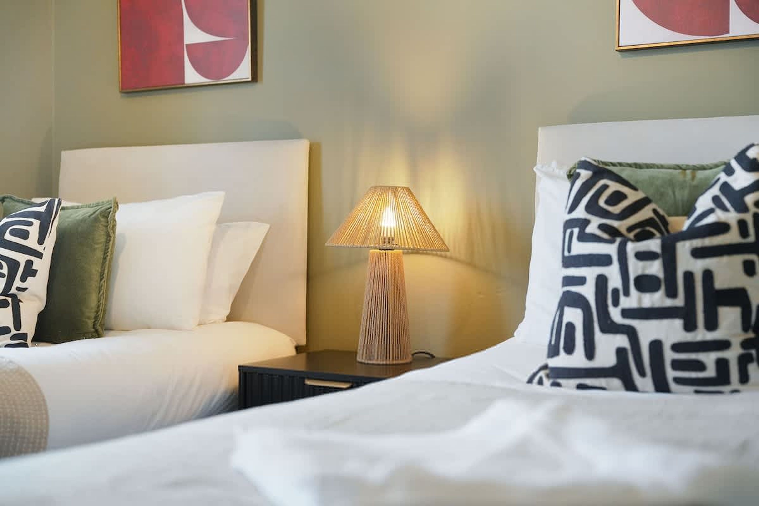 A hotel room with a bed, a nightstand, a lamp, and two pillows.