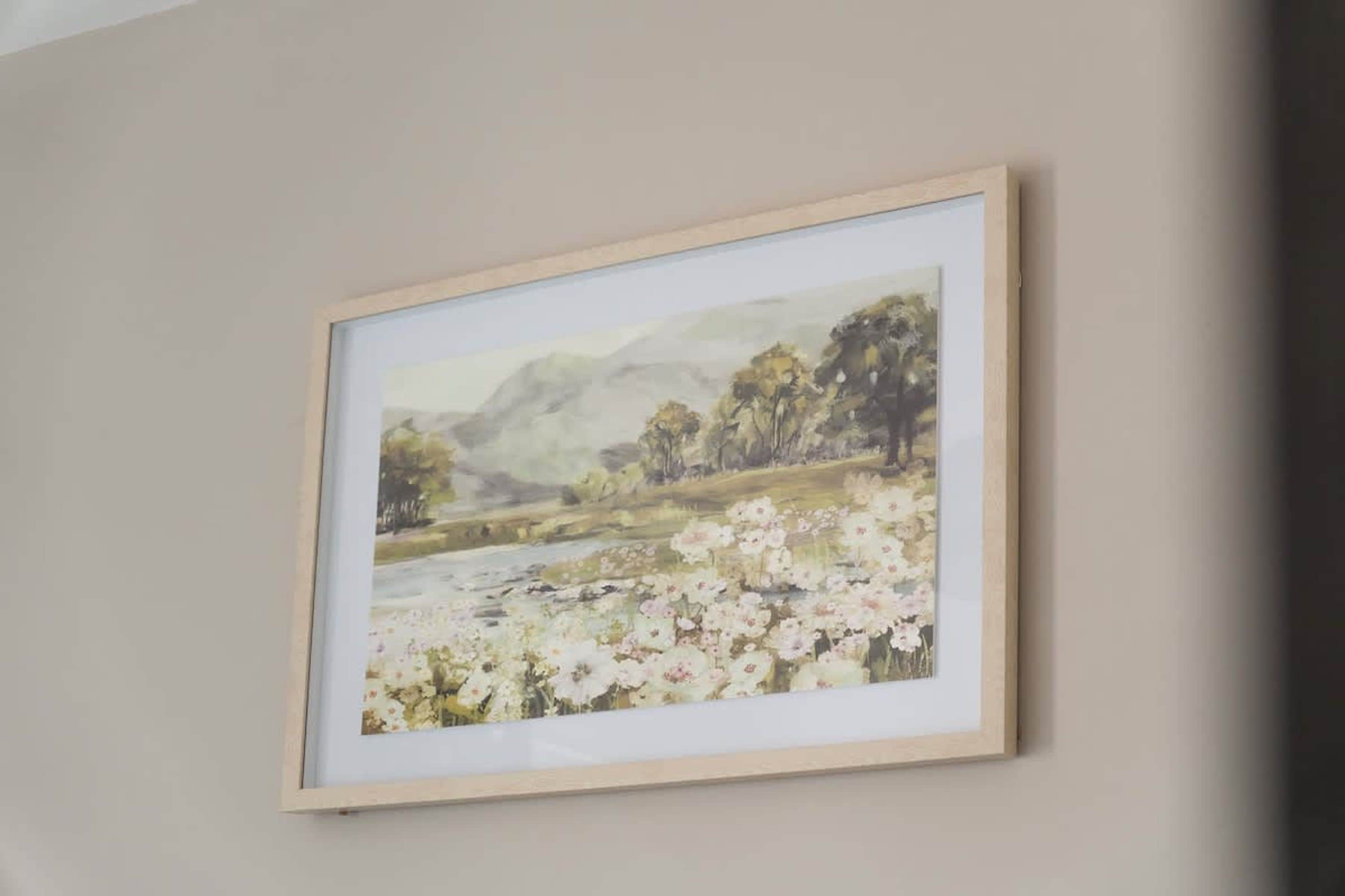 A framed landscape painting on a wall.
