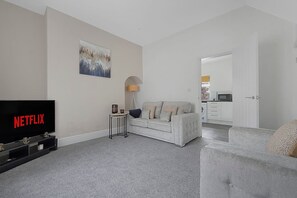A living room with a sofa, a television, and a painting on the wall. - Family Coastal Three Bedroom House Parking and Wifi (Saltburn-by-the-Sea)