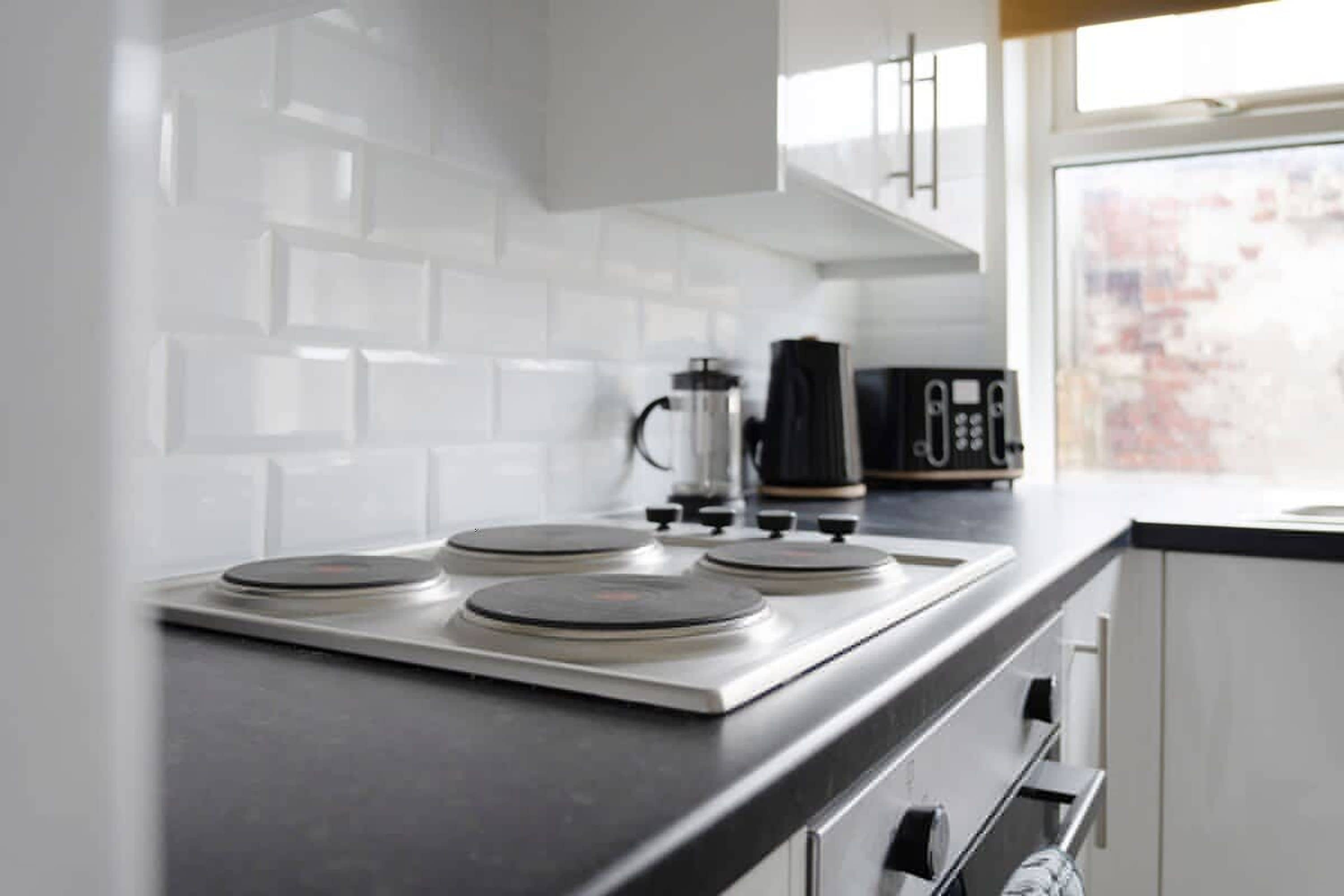 A kitchen with a modern stove, a coffee maker, and a window with a view.