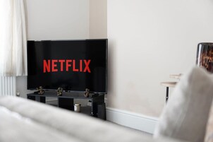 Una sala de estar moderna con un televisor de pantalla plana grande que muestra el logotipo de Netflix.