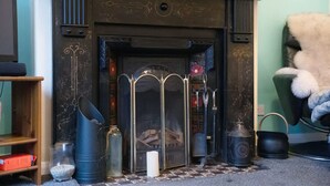 A fireplace with a metal grate, a candle, and decorative items on the mantel. - 2BR in Dundee Free Wifi and Indoor Fireplace (Darlington)