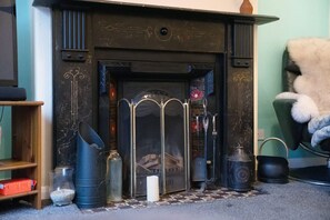 A fireplace with a metal grate, a candle, and decorative items on the mantel. - 2BR in Dundee Free Wifi and Indoor Fireplace (Darlington)