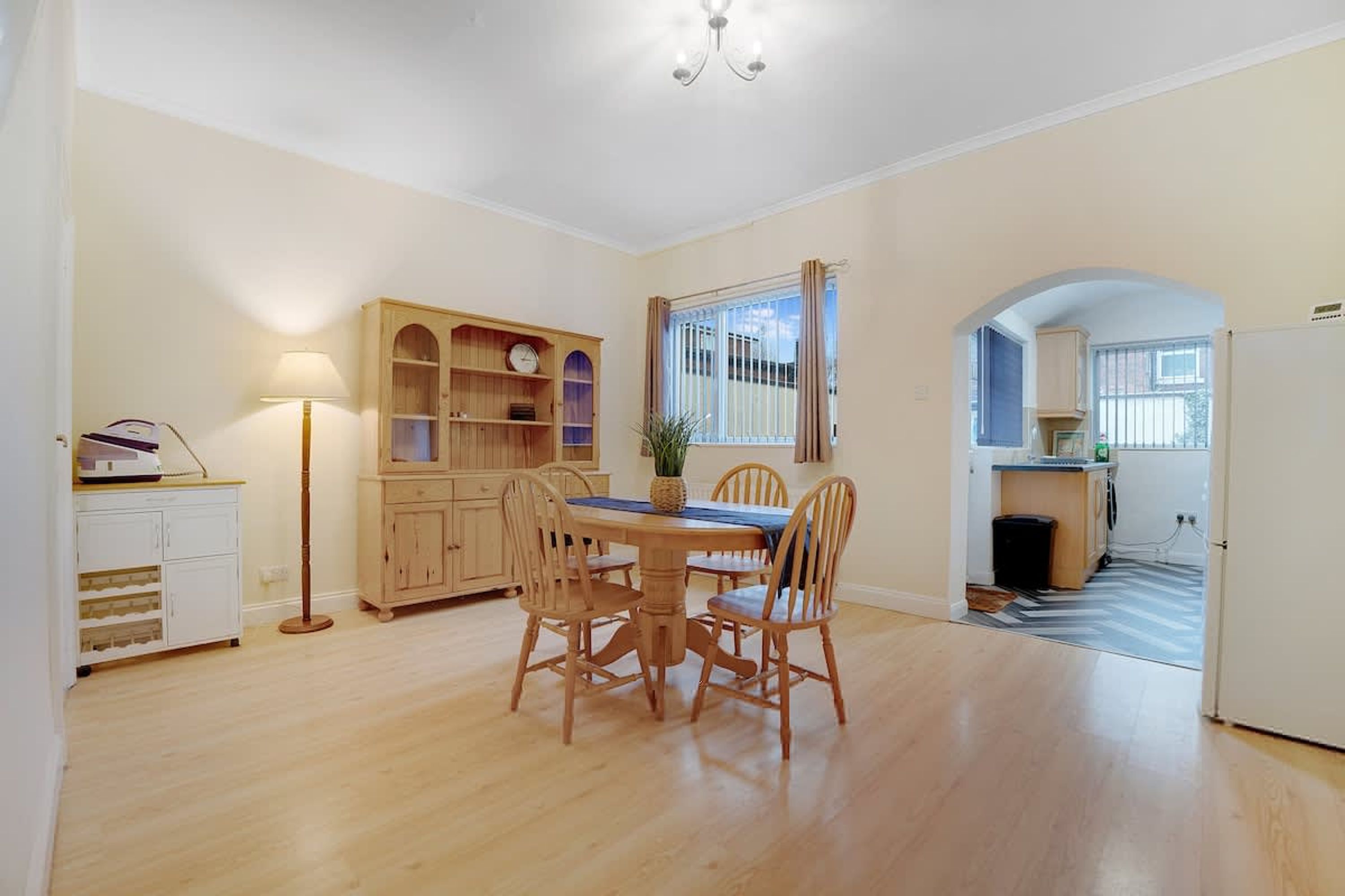 Un comedor con una mesa y sillas de madera, una lámpara y una estantería.