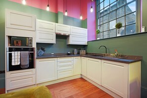 Una cocina con armarios blancos, un microondas y un lavamanos.