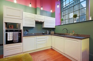 Una cocina con armarios blancos, un microondas y un lavamanos.