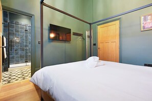 Une chambre d’hôtel avec un lit, une porte en bois, un miroir et une douche carrelée.