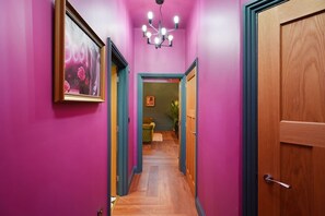 A hallway with pink walls, wooden doors, and a chandelier. - Central 2 Bed Near Barnard Castle Bowes Museum (Barnard Castle)