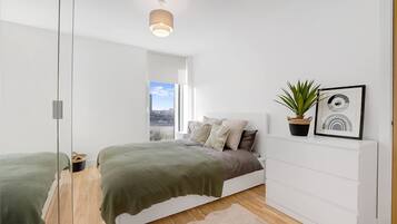 A modern bedroom with a bed, a potted plant, and a framed picture on the wall.