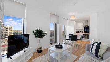 A modern living room with a flat-screen TV, a potted plant, a coffee table, and a sofa.