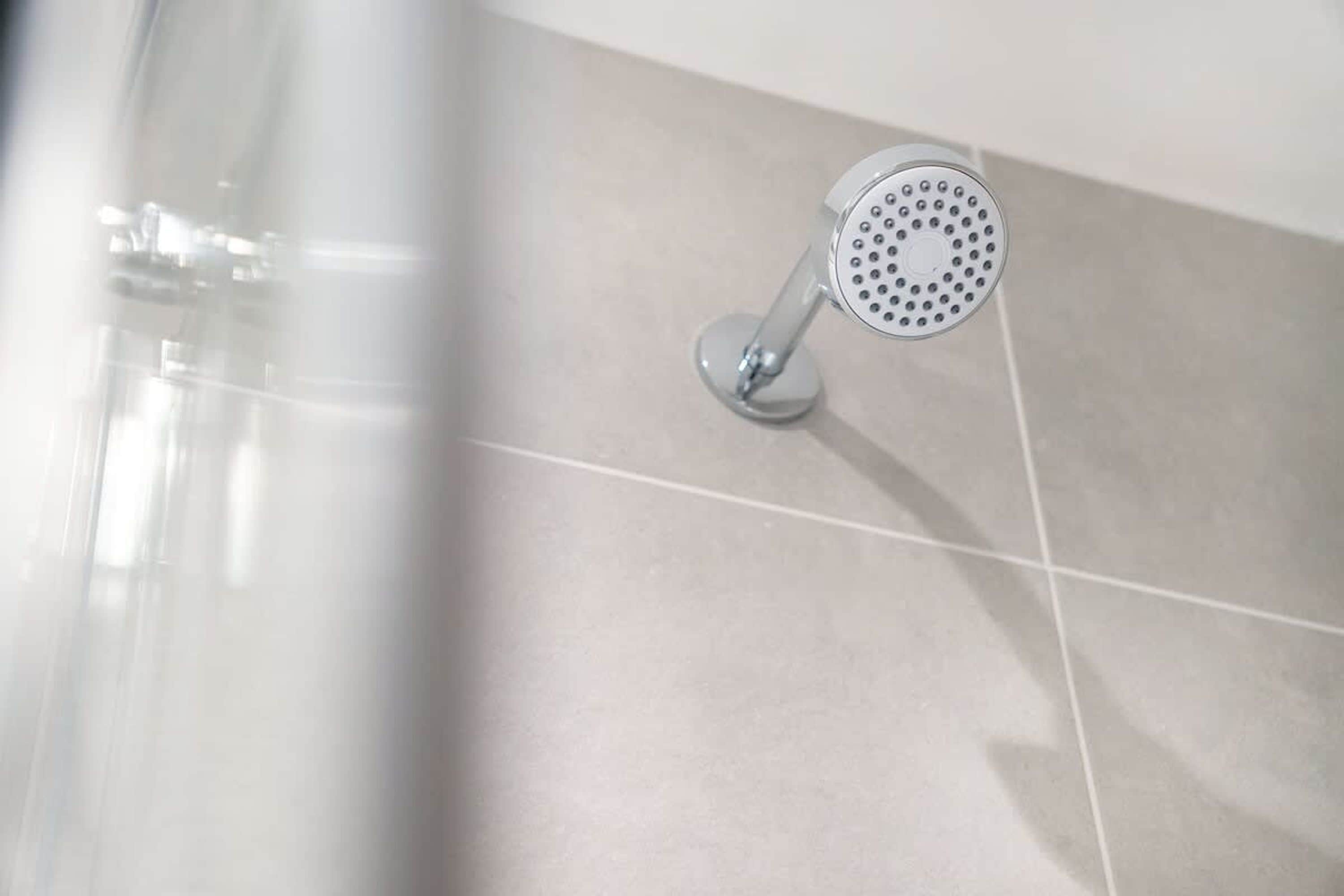 A showerhead with a circular design, mounted on a wall with a tiled surface.
