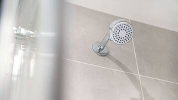 A showerhead with a circular design, mounted on a wall with a tiled surface.
