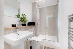 A modern bathroom with a sink, toilet, and glass-enclosed shower. - New 2BR in Media City Free Wifi (Salford)