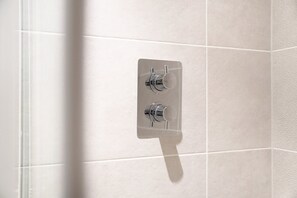 A bathroom with a shower area, featuring a glass shower enclosure and a wall-mounted faucet. - New 2BR in Media City Free Wifi (Salford)