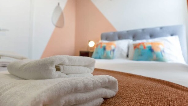 A neatly made bed with a white towel, a brown blanket, and a grey headboard. - Spacious Five Bedroom Family Home Group Stay Wifi (Sunderland)