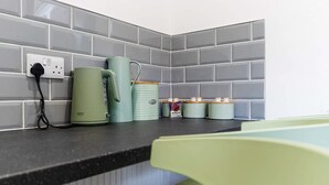 A kitchen counter with a kettle, a mug, and a canister. - Spacious Five Bedroom Family Home Group Stay Wifi (Sunderland)