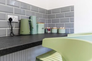 A kitchen counter with a kettle, a mug, and a canister. - Spacious Five Bedroom Family Home Group Stay Wifi (Sunderland)