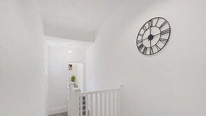 A staircase with a white railing leading to a landing with a clock on the wall. - Spacious Five Bedroom Family Home Group Stay Wifi (Sunderland)