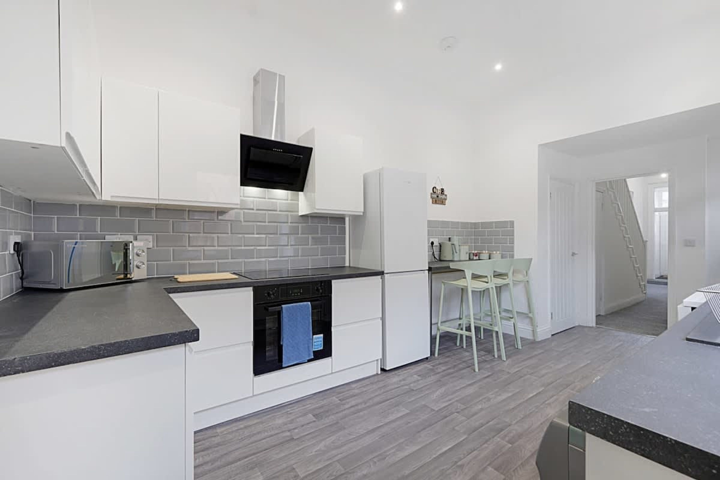A modern kitchen with white cabinetry, a black countertop, and a built-in oven.