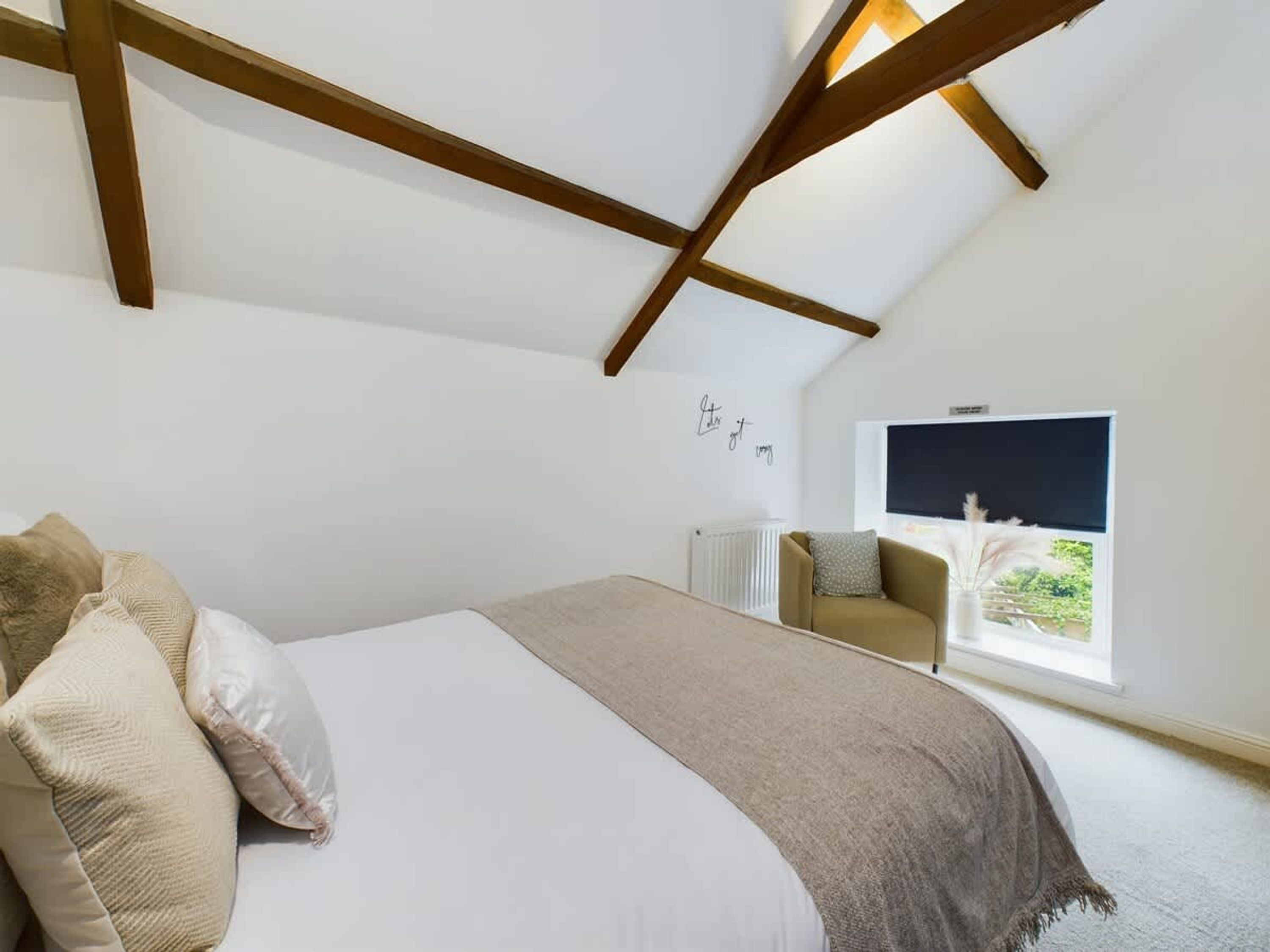 Un dormitorio con cama, ventana con vistas, radiador y una pared con un letrero.