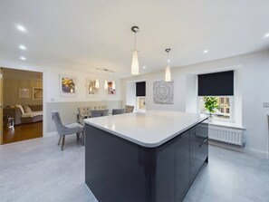 A modern kitchen with a central island, pendant lighting, and a dining area with chairs. - Charming 3-bedroom Home in the Heart of Stanhope (Bishop Auckland)