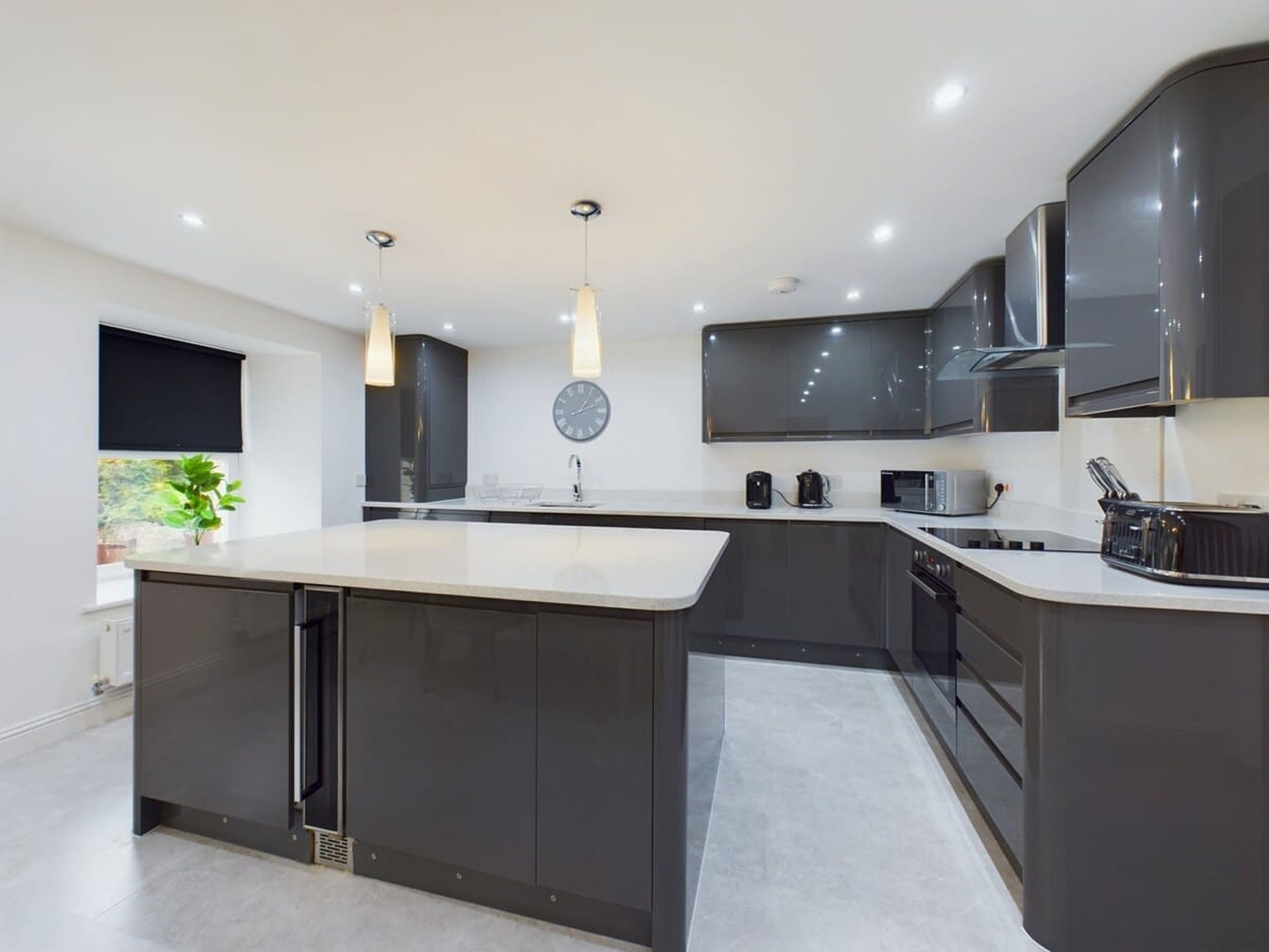 Una cocina moderna con una isla central, muebles oscuros y electrodomésticos de acero inoxidable.