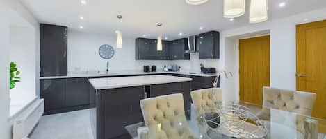 A modern kitchen with dark cabinets, a central island, and pendant lighting.