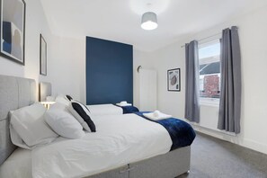 A modern hotel room with a large bed, a bedside table, a window with curtains, and a view of the outside. - Stylish Home Near Darlington Town Centre (Darlington)
