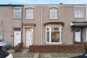 A terraced house with a front door, a bay window, and a small front garden. - Stylish Home Near Darlington Town Centre (Darlington)