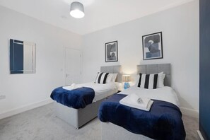 Une chambre d’hôtel avec deux lits, une porte et deux tableaux encadrés au mur.