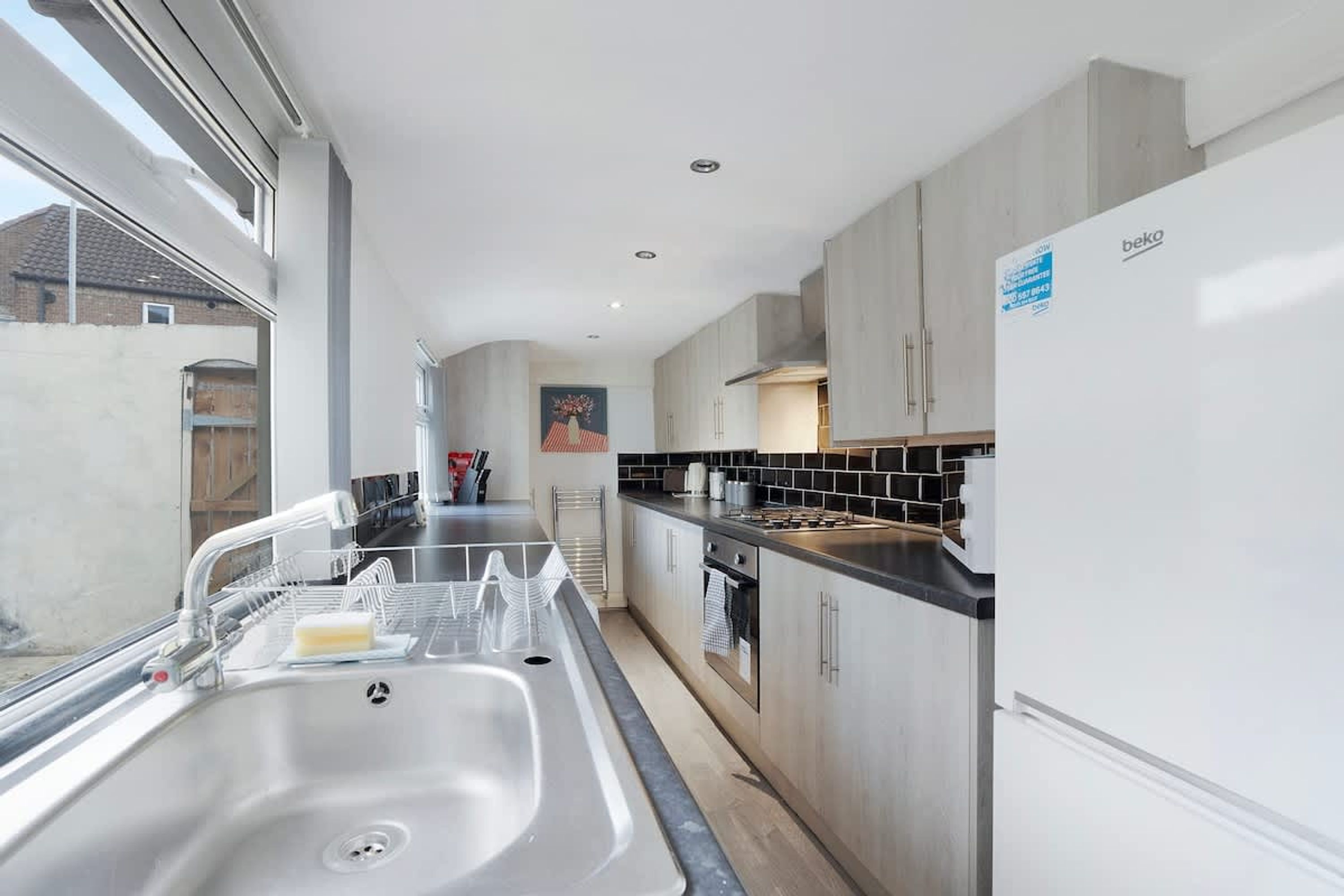 A modern kitchen with a stainless steel sink, a stove, and a refrigerator.