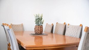 Una mesa de madera para comer con seis sillas, un centro de mesa tejido y una pila de libros.