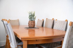 Ein Holztisch mit sechs Stühlen, einem gewebten Tischläufer und einem Stapel Bücher.