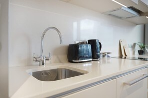 A modern kitchen with a stainless steel sink, a coffee maker, and a toaster. - Stylish Studio Apartment in Manchester (Salford)