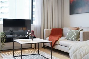 A living room with a flat-screen TV, a coffee table, a sofa, and a potted plant. - Stylish Studio Apartment in Manchester (Salford)