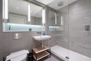 A modern bathroom with a toilet, sink, and shower. - Stylish Studio Apartment in Manchester (Salford)