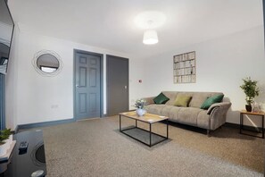 Ein Wohnzimmer mit Sofa, Couchtisch, Pflanze und einem Wandbild.