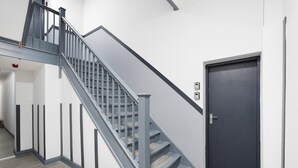 En modern trappa med ett metallräcke, en mörk dörr och en vägg i en ljus färg.