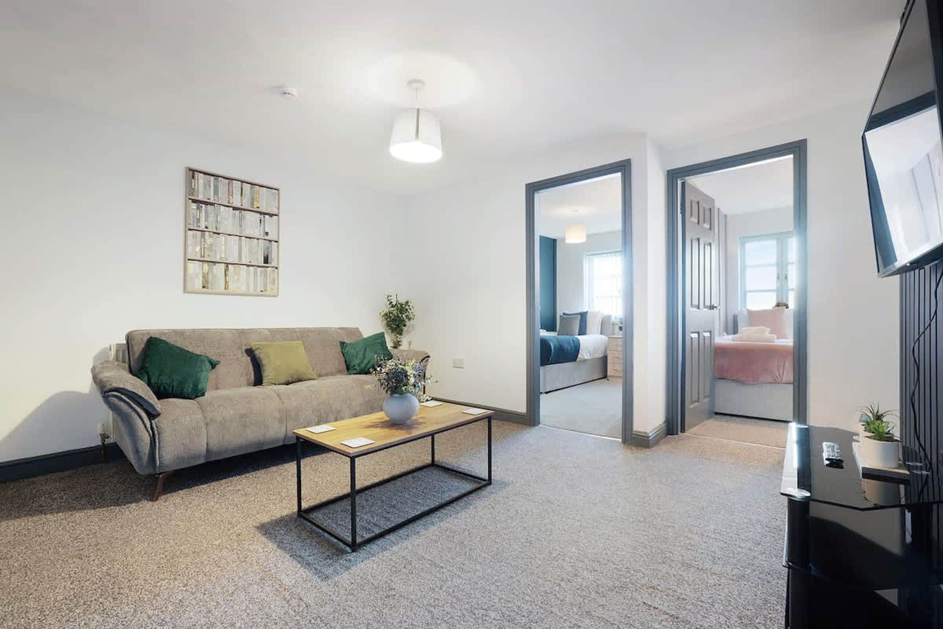 Ein modernes Wohnzimmer mit einer Couch, einem Couchtisch und einem Spiegel, der einen weiteren Raum reflektiert.