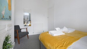 Ein Hotelzimmer mit einem Bett, einem Sessel, einem Heizkörper und einem Bild an der Wand.