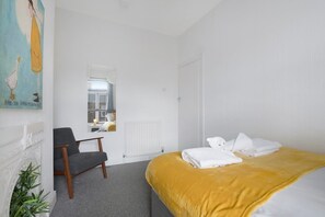 Ein Hotelzimmer mit einem Bett, einem Sessel, einem Heizkörper und einem Bild an der Wand.