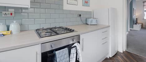 A modern kitchen with a gas stove, a toaster, and a refrigerator.