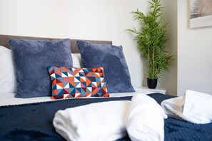 A neatly made bed with blue and white bedding, a geometric patterned pillow, and a potted plant beside it. - 2BR in Brighton Road With Wifi Parking Smart TV (Darlington)