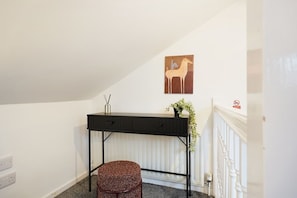 A room with a black desk, a woven stool, a wall-mounted plant, and a painting of a horse. - Modern 4BR With Easy Access to Town and Station (Darlington)
