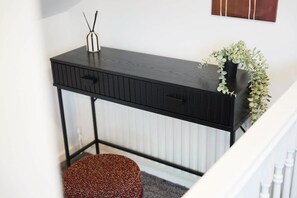 A black console table with a plant, a candle, and a small stool. - Modern 4BR With Easy Access to Town and Station (Darlington)